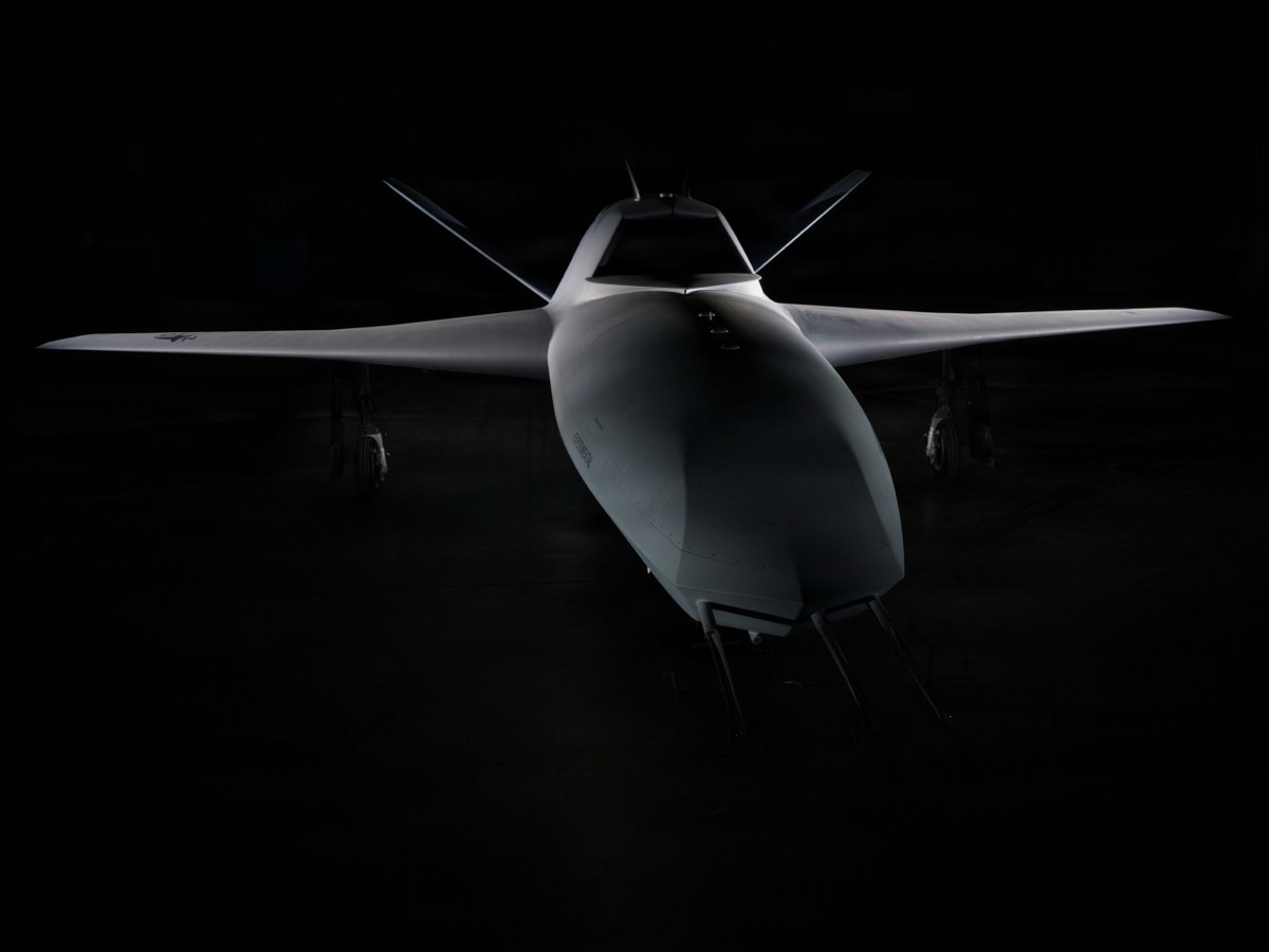 An uncrewed aircraft lit against a dark hangar background.